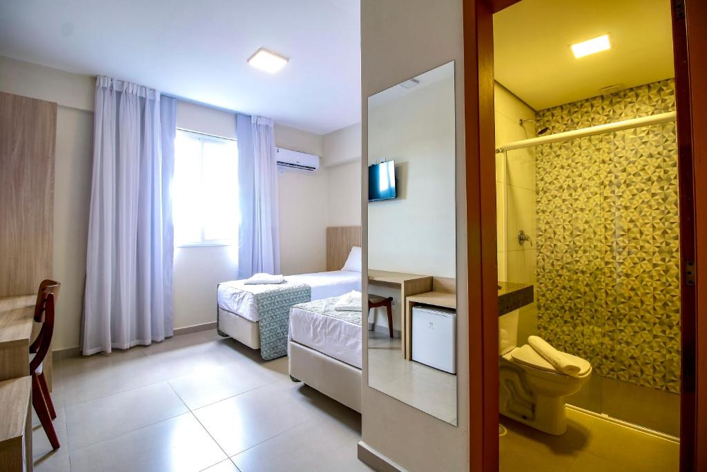 a small room with two beds and a bathroom at MLG Hotel in Mogi das Cruzes