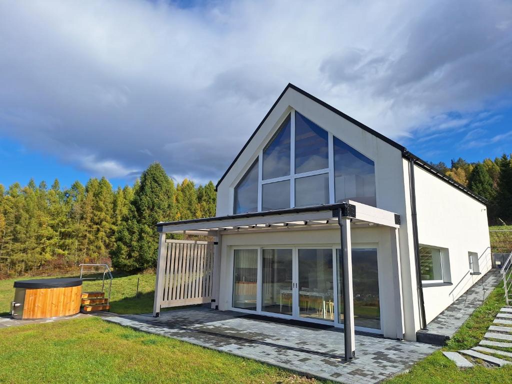 Cette petite maison blanche dispose de grandes fenêtres. dans l'établissement Willa Agrestówka z balią na wyłączność, à Milówka