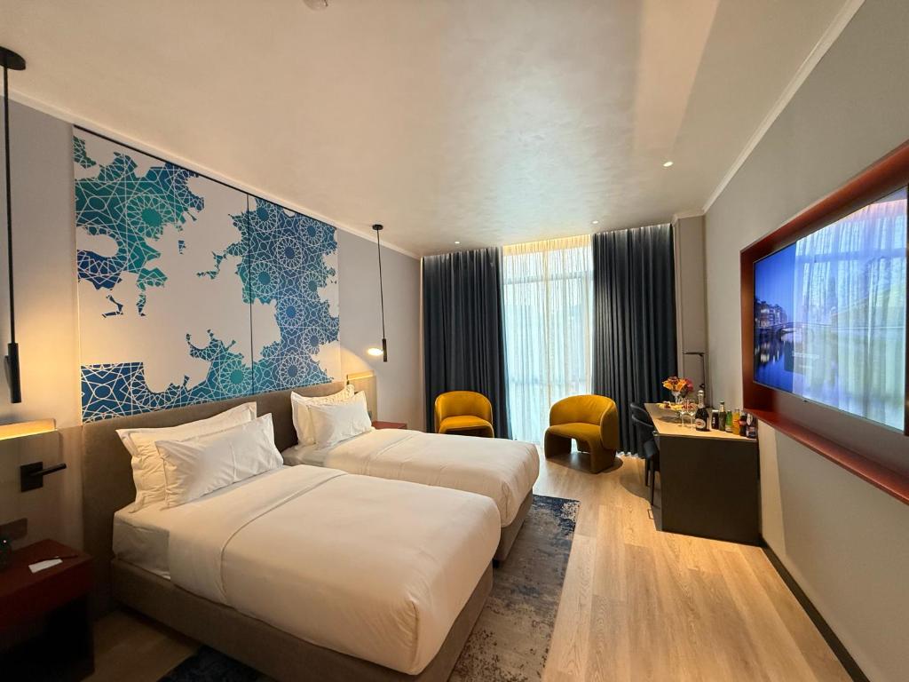 a hotel room with two beds and a flat screen tv at Khorazm Hotel in New Uzbekistan Park in Teshabayguzar