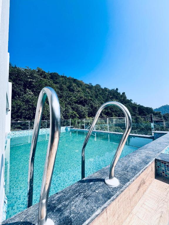 a swimming pool with two metal rails next to the water at Roots & Peaks Wellness Hotel in Rishīkesh