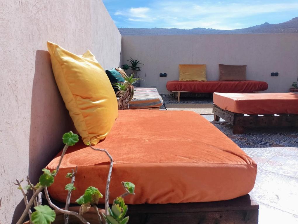 een bed met een oranje kussen op een terras bij Water Dance in Imsouane