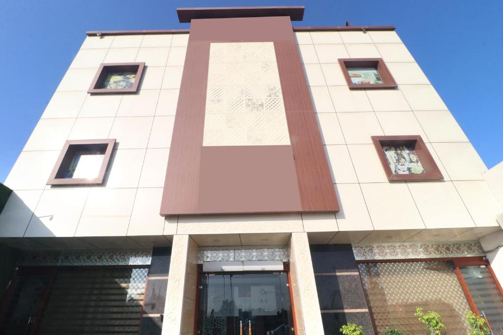 a tall white building with windows at Hotel O B1 in Kartārpur