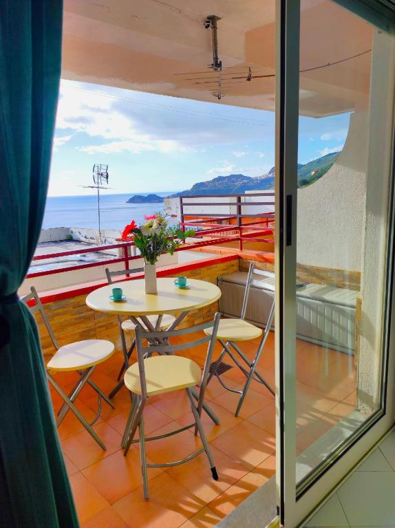 a table and chairs on a balcony with a view of the ocean at Bellavista apartment Letojanni in Letojanni