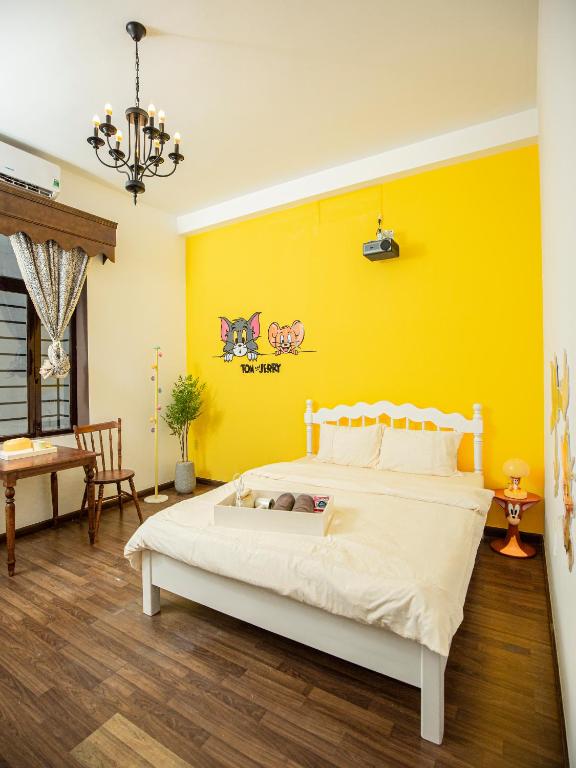 a bedroom with a white bed and a yellow wall at Nàng Homestay Studio in Thu Dau Mot