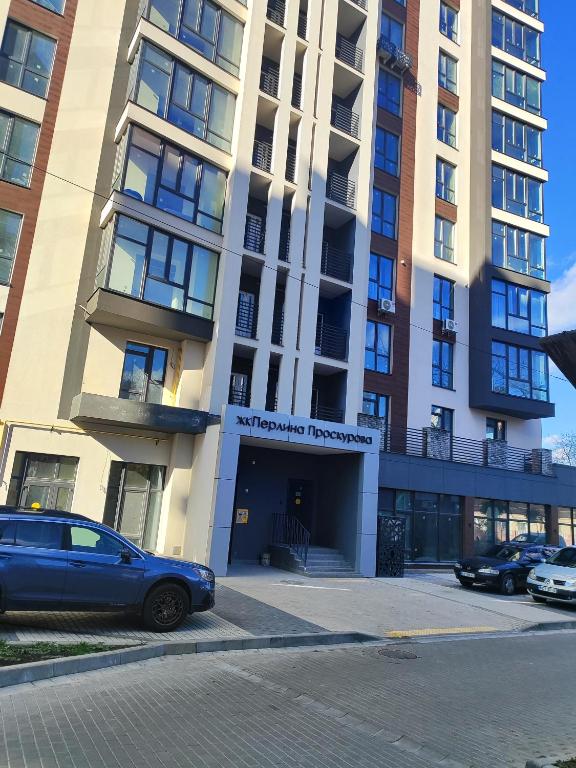 a building with a car parked in front of it at Апартаменты у новому будинку біля Либідь Плази-Ощадбанк in Khmelʼnytsʼkyy