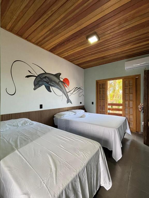 a bedroom with two beds with a fish on the wall at Suítes da Sereia in Cananéia