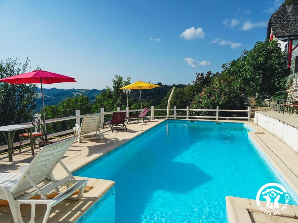 Una piscina con sillas y sombrillas en una casa. en Le Sécadou de Campristinie, en Le Fel