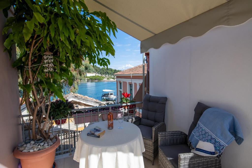 een balkon met een tafel en stoelen en uitzicht op het water bij Dora Studios by PaxosRetreats in Gaios