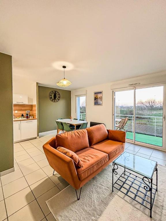 a living room with a brown couch and a table at Puilborin, appartement cosy, avec terrasse in Puilboreau
