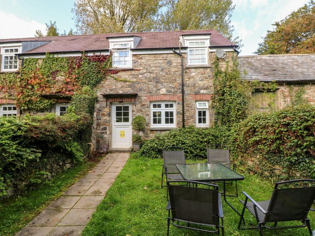 an old stone house with a table and chairs in front of it at Swallows Cottage in Walton East