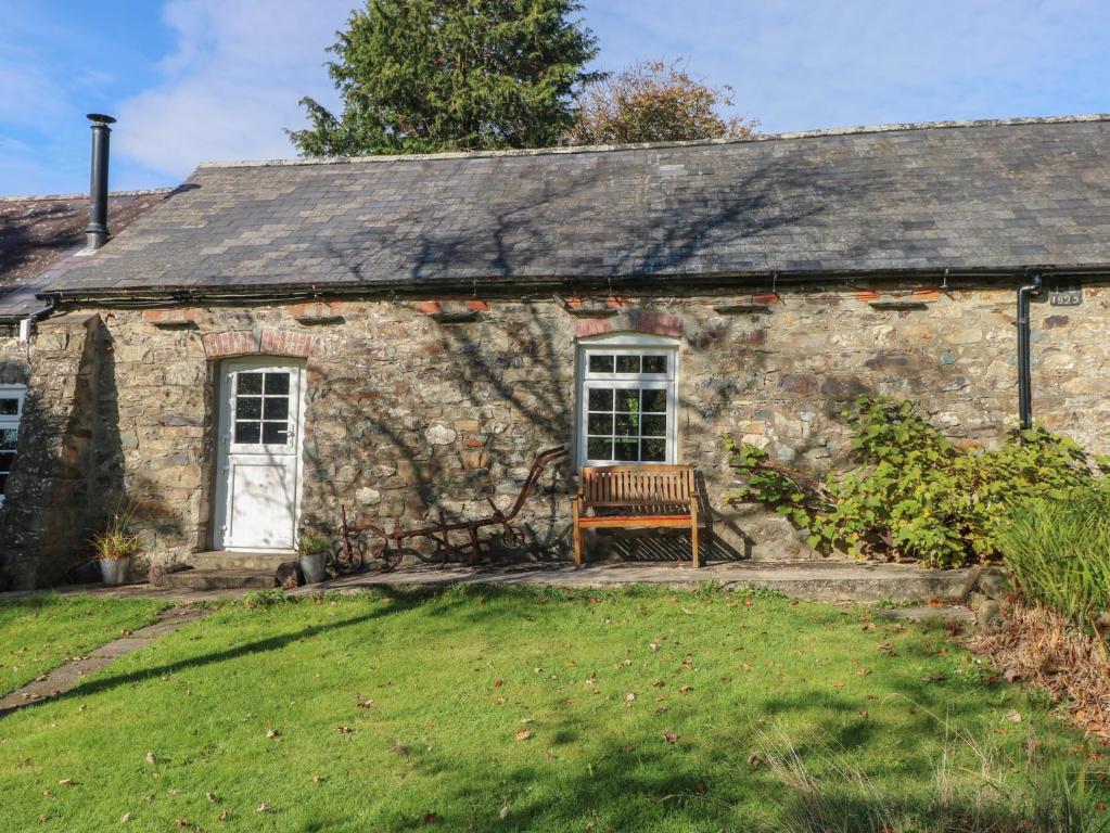 an old stone cottage with a bench in front of it at Granary Cottage in Walton East