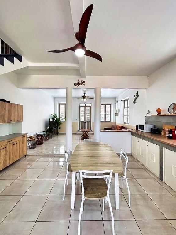 a kitchen with a table and a ceiling fan at Kaz Créole, grande terrasse, piscine, parking in Le François