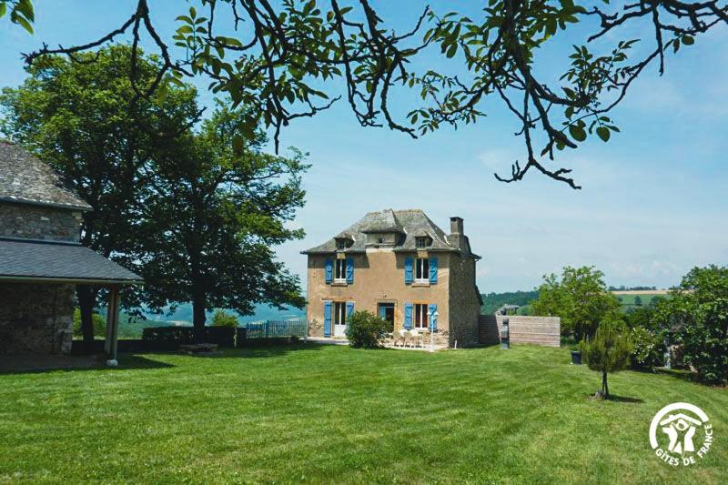 ein großes Haus auf einem Grasfeld mit einem Baum in der Unterkunft Bel Air in Peyrusse-le-Roc