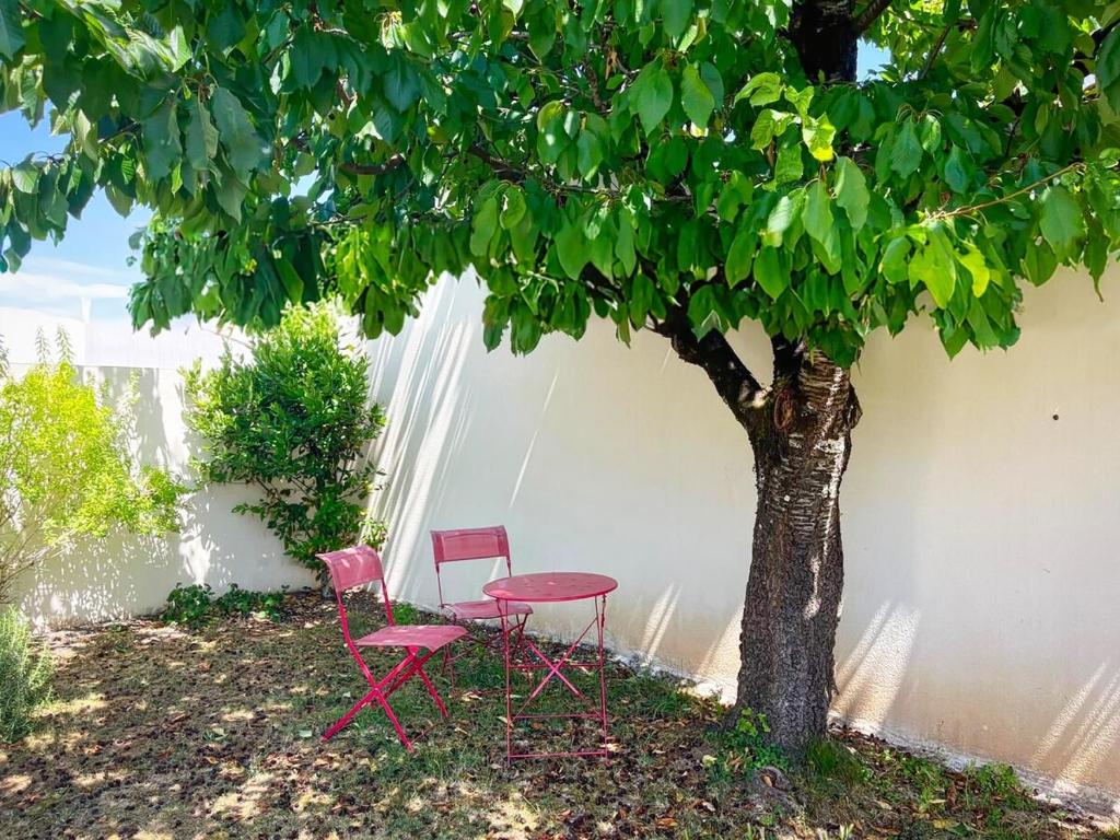a table and a chair next to a tree at Maison du bonheur in Aytré