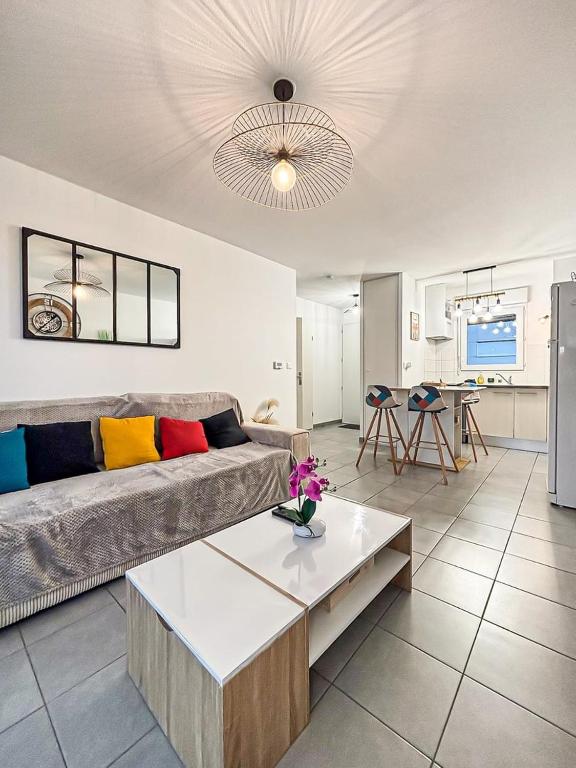 a living room with a couch and a table at Le Saint Éloi, Terrasse, confortable et parking in La Rochelle
