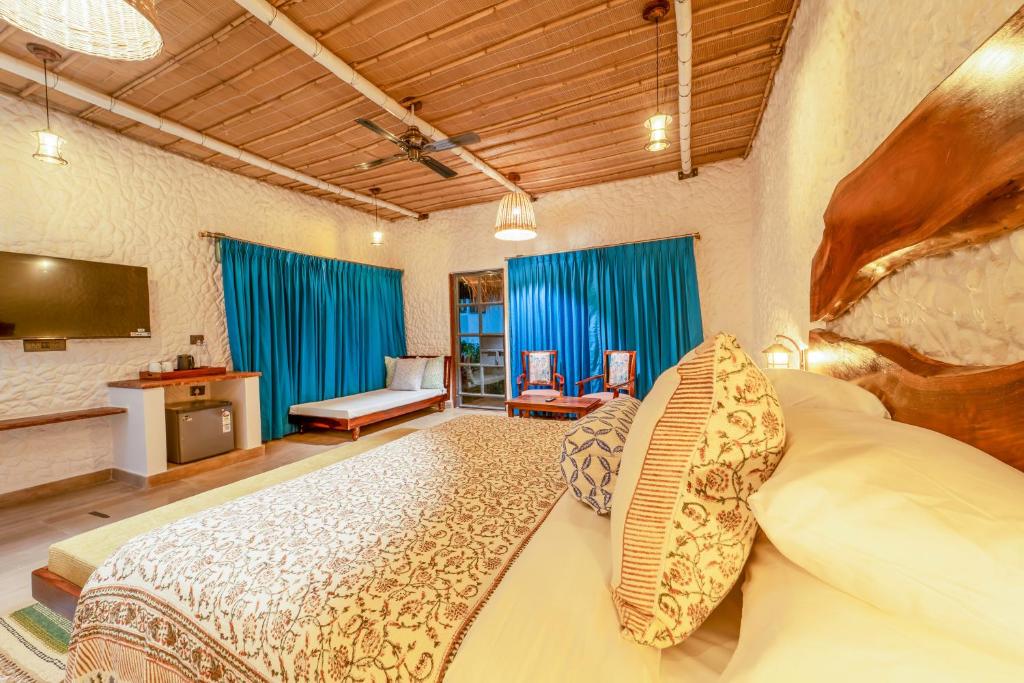 a bedroom with a large bed with blue curtains at Dunes & You - A Desert Retreat in Govindgarh