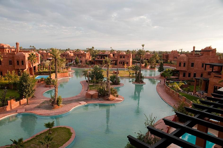 a pool in a resort with palm trees and buildings at Palacio Hôtel Condominium Marrakech in Marrakech