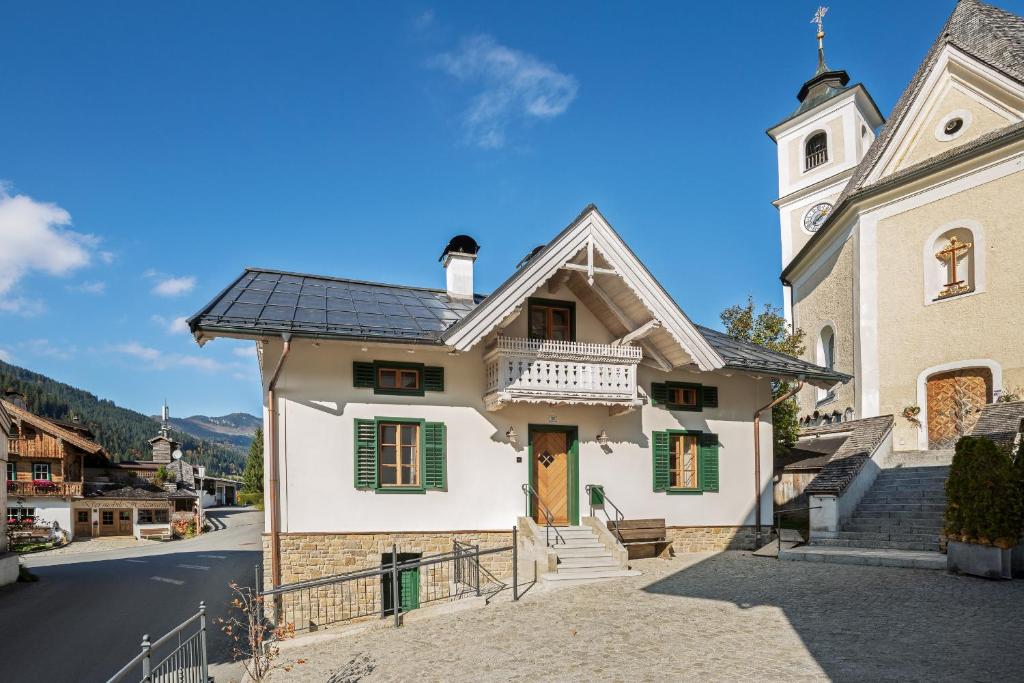 a white house with a clock tower on a street at Das Krämerhaus mit Sauna by Alpine Host Helpers in Kirchberg in Tirol