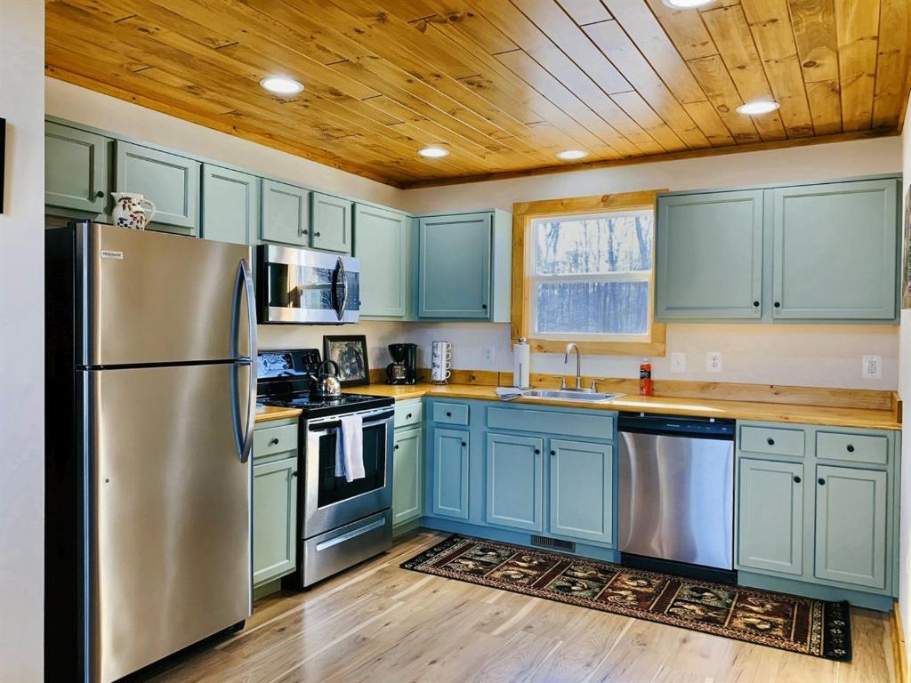 eine Küche mit blauen Schränken und einem Kühlschrank aus Edelstahl in der Unterkunft Oak Tree cabin near the Shenandoah River in Oak Hill