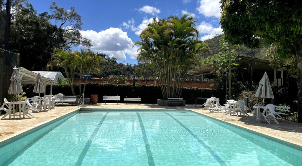 a large swimming pool with chairs and umbrellas at Pousada Sitio Sossego in Petrópolis
