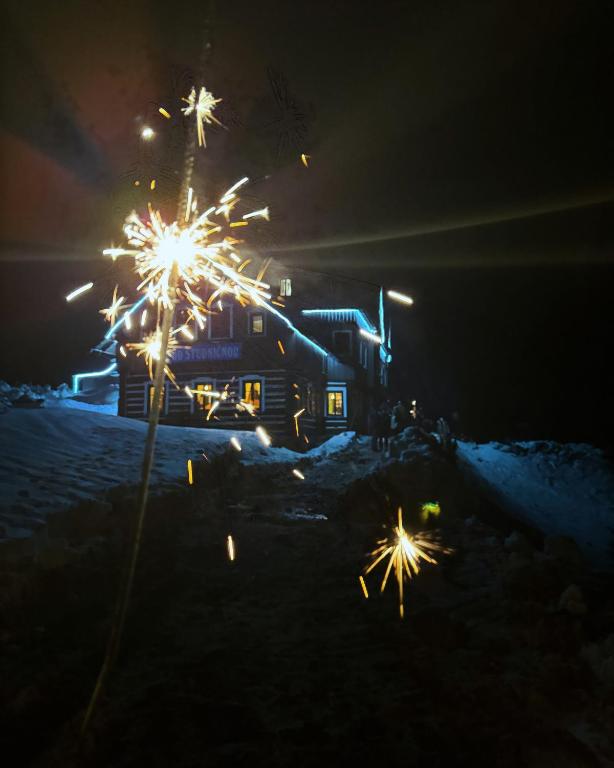 a house with sparklers in the snow at night at Chata pod Studničnou in Pec pod Sněžkou