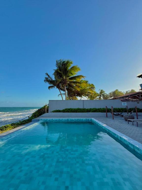 a swimming pool with a view of the ocean at Flat StudioMar - beira mar até 4 p - pé na areia in Coruripe