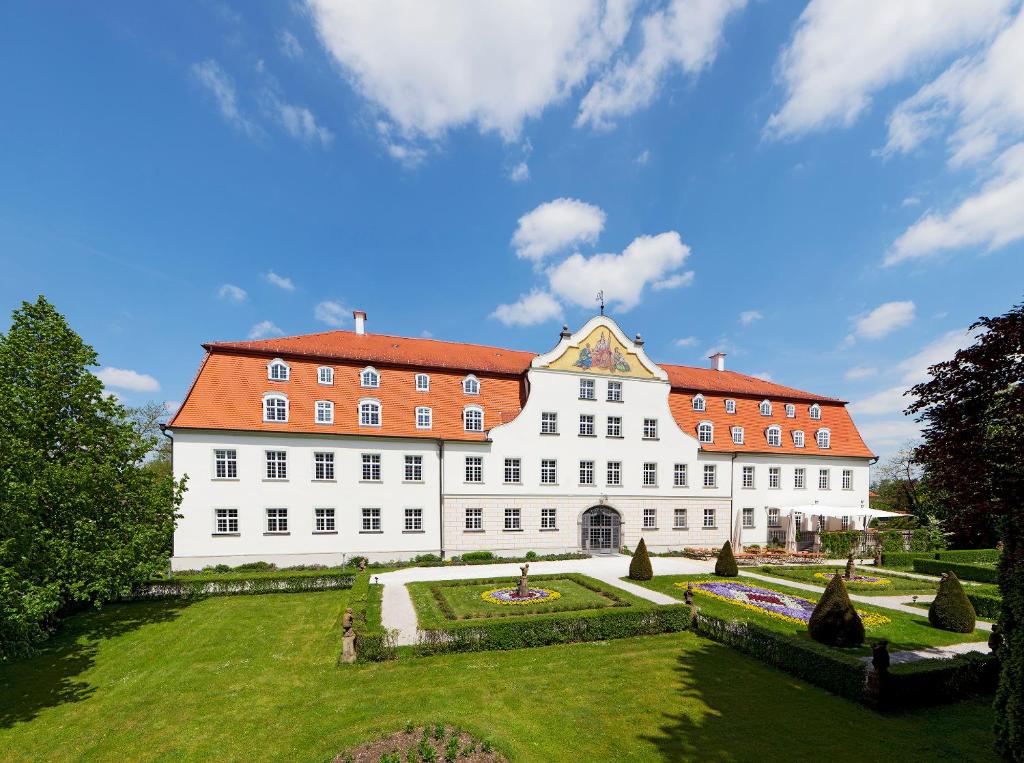 ein großes weißes Gebäude mit orangefarbenem Dach in der Unterkunft Schloss Lautrach in Lautrach