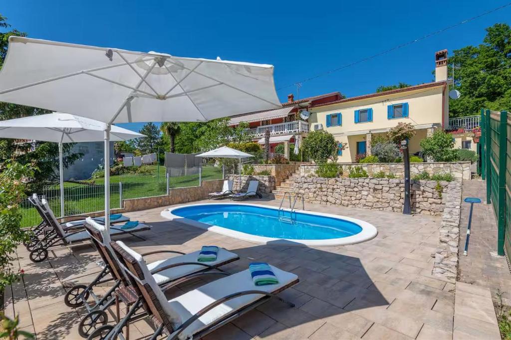 a swimming pool with two chairs and an umbrella at Villa Emma in Lanišće