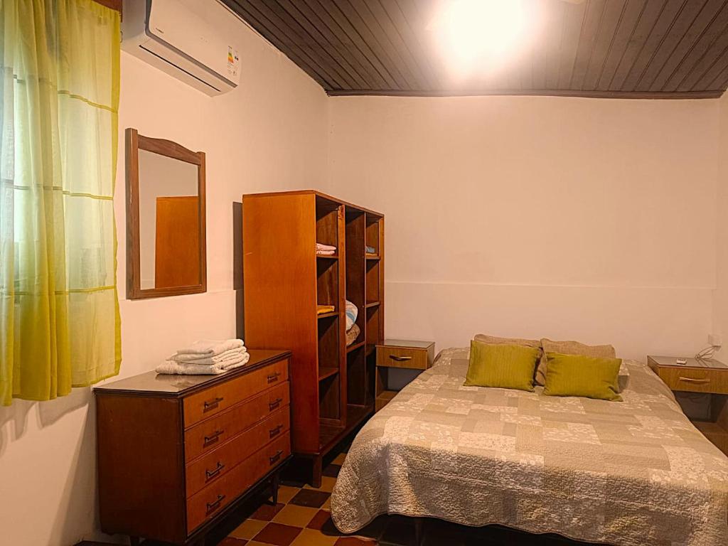 ein Schlafzimmer mit einem Bett, einer Kommode und einem Spiegel in der Unterkunft Casa Baqué in Colonia del Sacramento