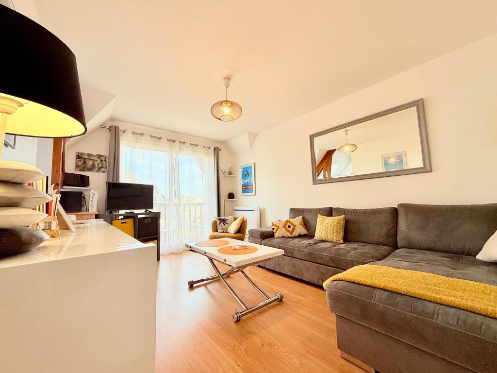 ein Wohnzimmer mit Sofa und Tisch in der Unterkunft Cabourg Mathilde in Cabourg