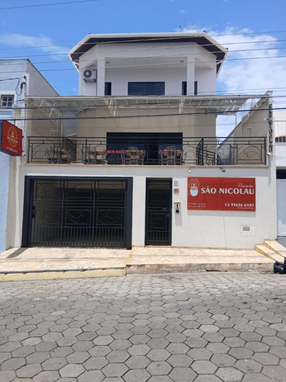 a white building with black doors and a balcony at Pousada São Nicolau in Cachoeira Paulista