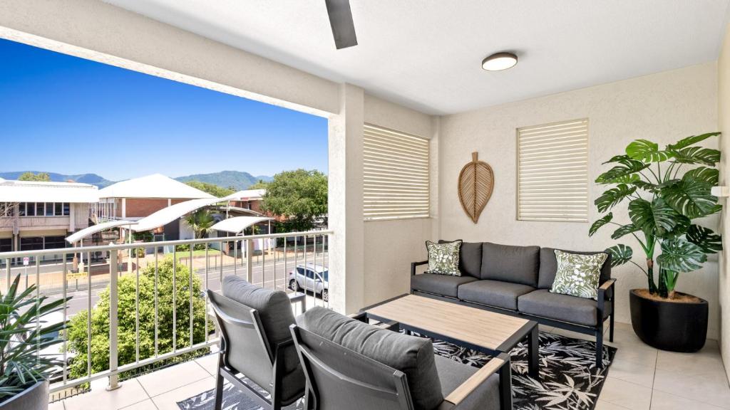 un patio con divano e sedie sul balcone. di Sundown on Grafton St a Cairns