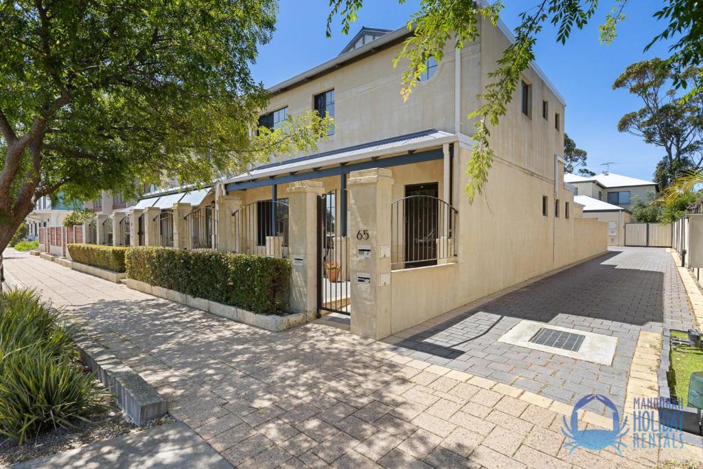 a building on a street with trees and a sidewalk at Mandurah Luxury on Sutton in Mandurah