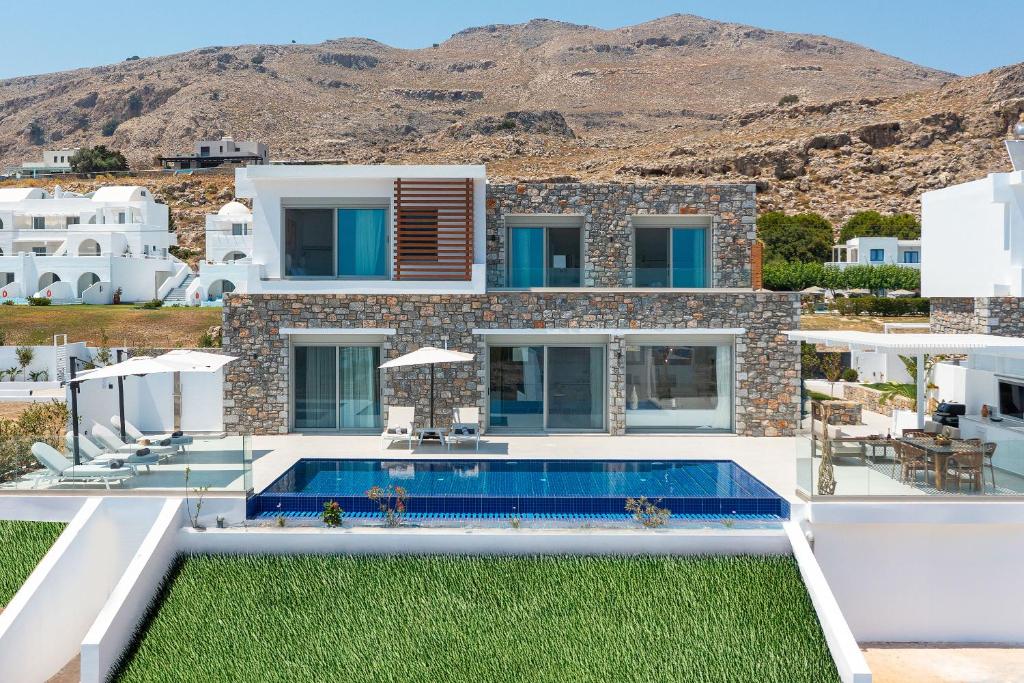 a villa with a swimming pool in front of a house at Lindian Poem Villas in Lindos