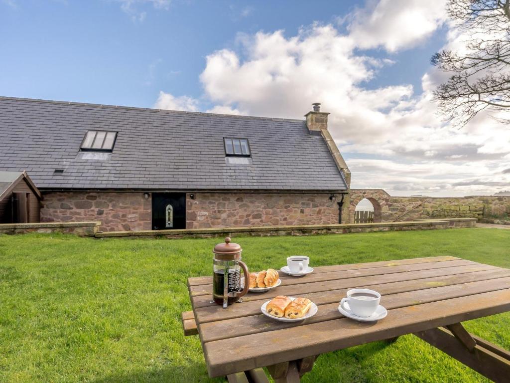 a picnic table with two plates of food on it in front of a building at 2 Bed in Bamburgh 36344 in Kyloe
