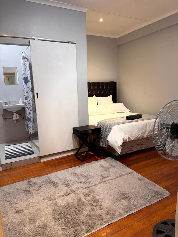 a bedroom with a bed and a fan and a room with a fan at HavenTrust Guest house in Goodwood