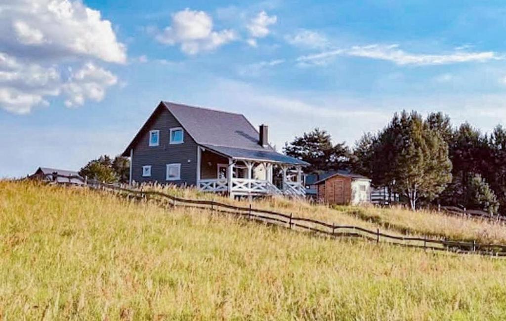 a black house on a hill in a field at 3 Bedroom Awesome Home In Jasien in Jasień