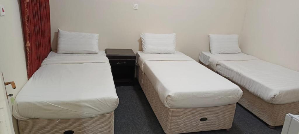a room with three twin beds with white sheets at نزل الاوئل in Al Madinah