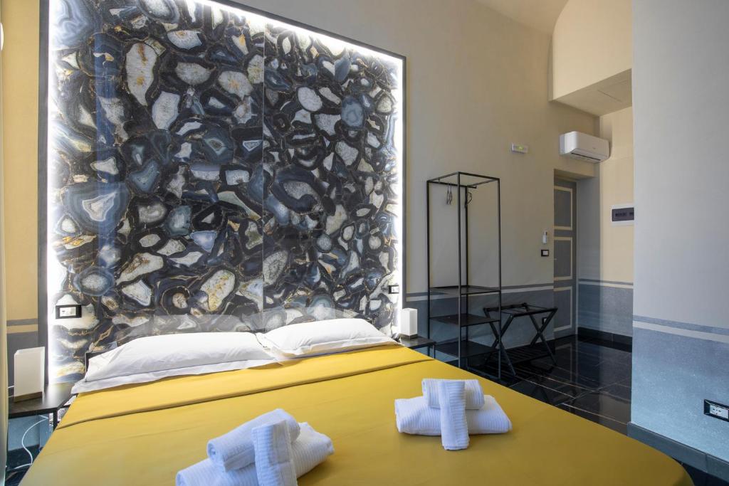 a bedroom with a yellow bed with towels on a table at Hotel Torre Orefici in Genoa