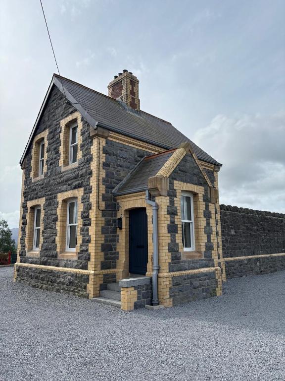 a small brick building with a black roof and a door at The Waterboard House in Magherasaul