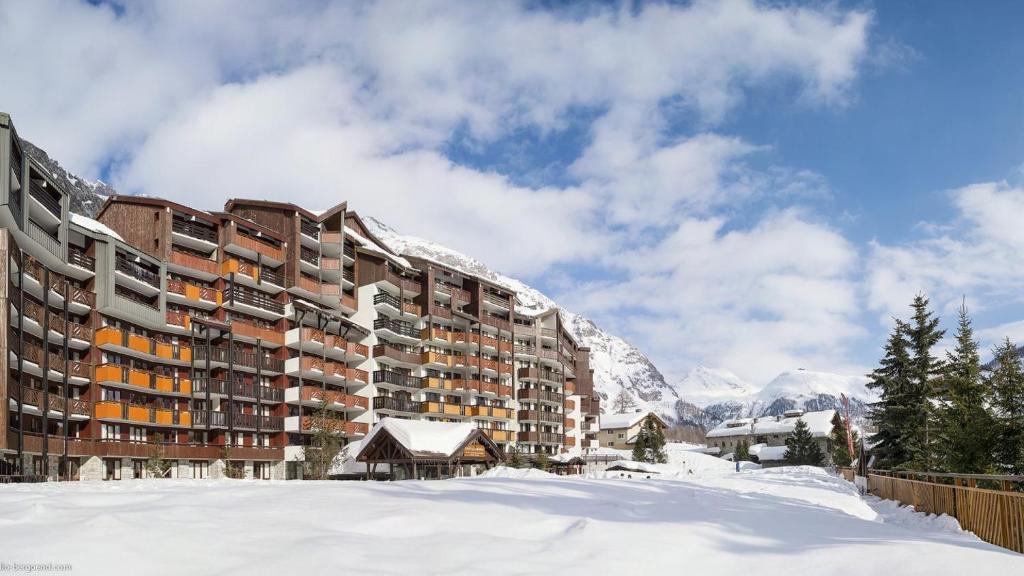 a building in the snow with mountains in the background at Résidence La Daille - Val-d'Isère in Val dʼIsère