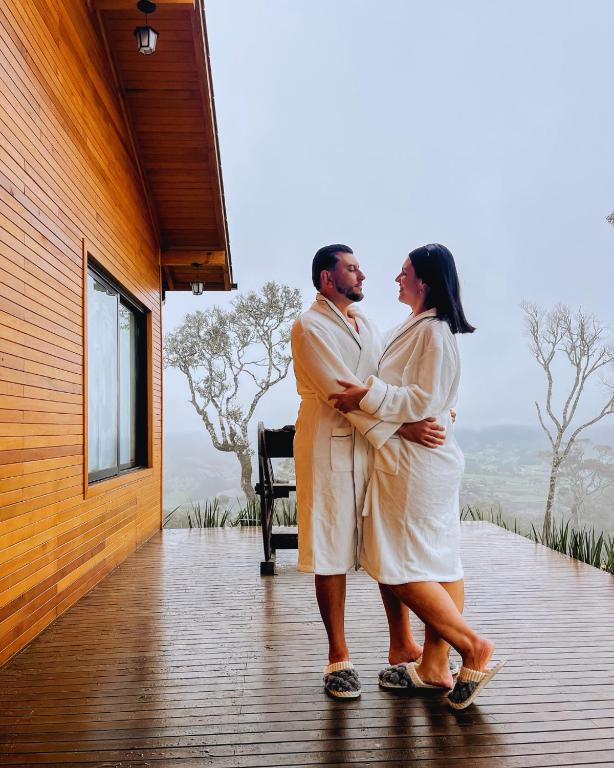 a man and a woman standing on a porch at Cabana Romântica, Banheira, Lareira e Privacidade in Bom Retiro