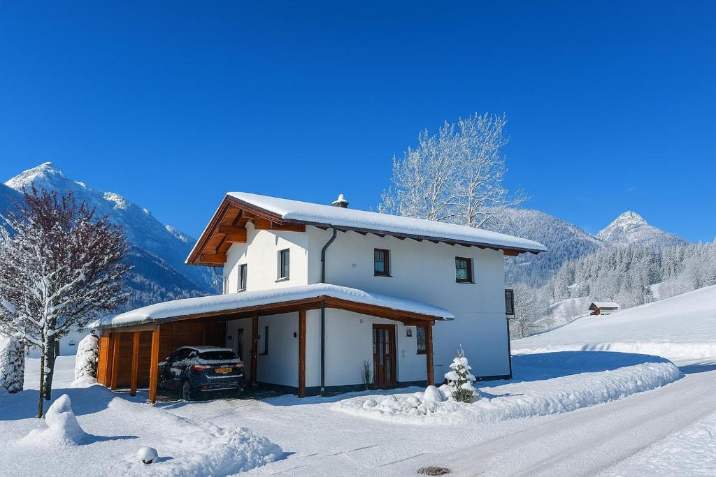 a white house with a car parked in the snow at Chalet Giusto in Kötschach