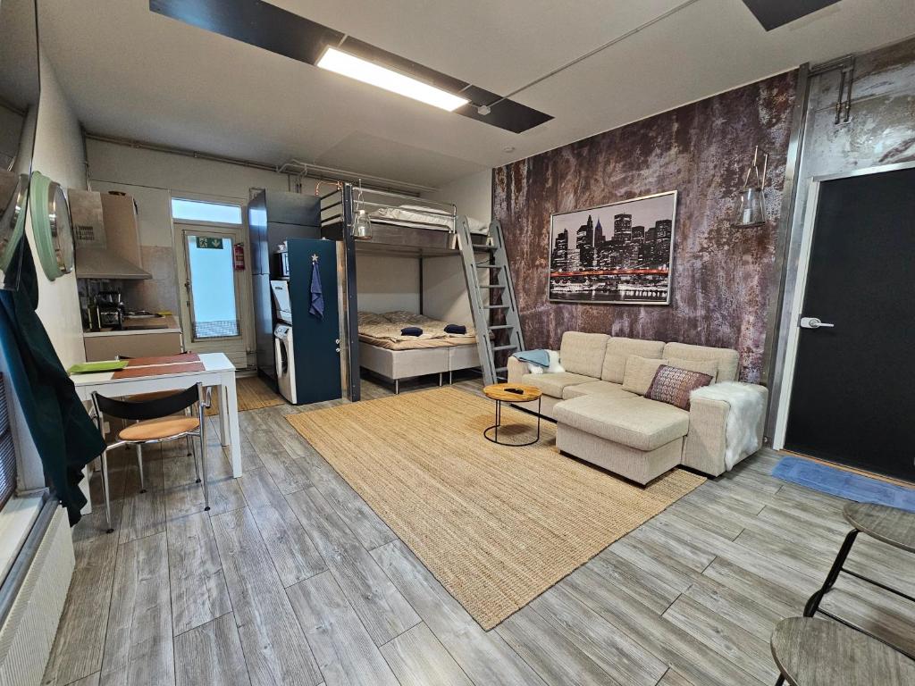 a living room with a couch and a kitchen at Loft style big studio for 2-4 in Pikku Huopalahti in Helsinki