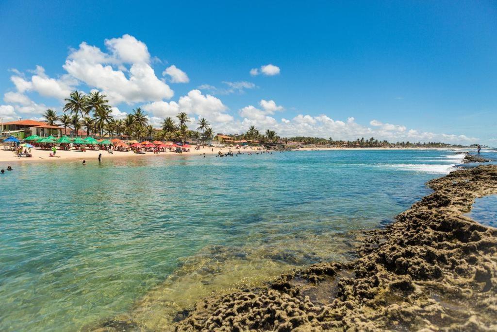 a beach with people and umbrellas in the water at Casa dos Corais in Cabo de Santo Agostinho