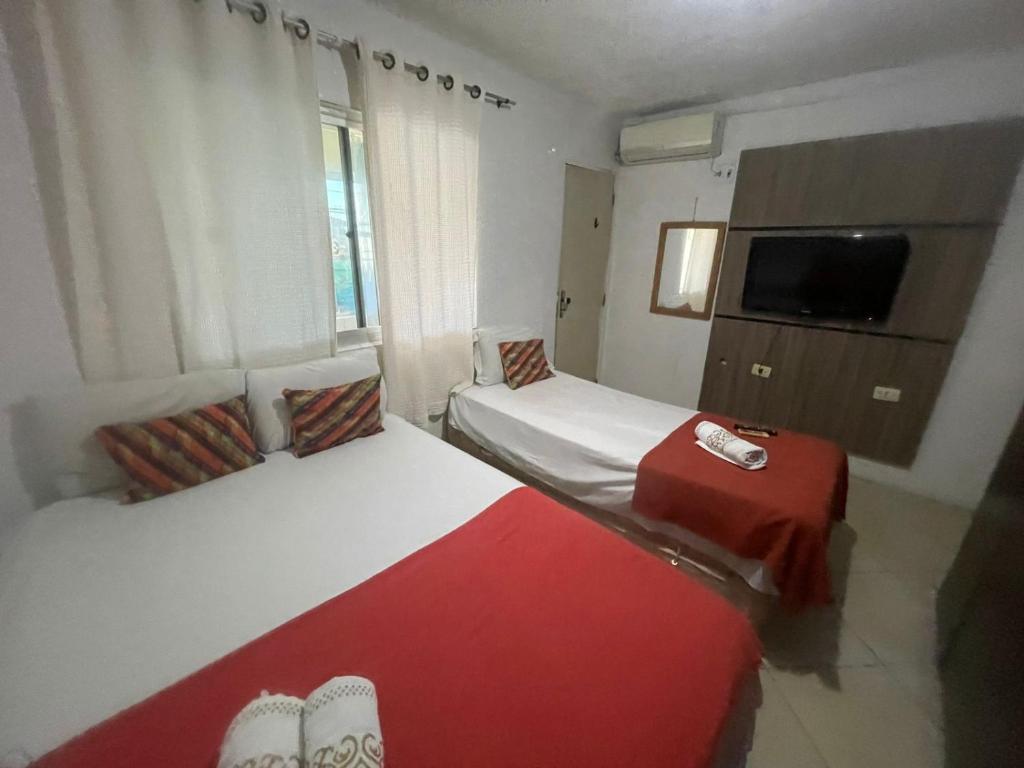 um quarto de hotel com duas camas e uma televisão em Pousada Casa Mar de Pajuçara em Maceió