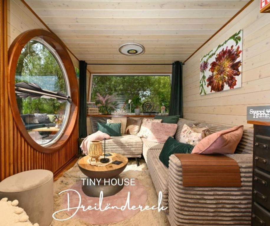 Una pequeña sala de estar con un sofá y una mesa. en Tiny House Dreiländereck, en La Calamine