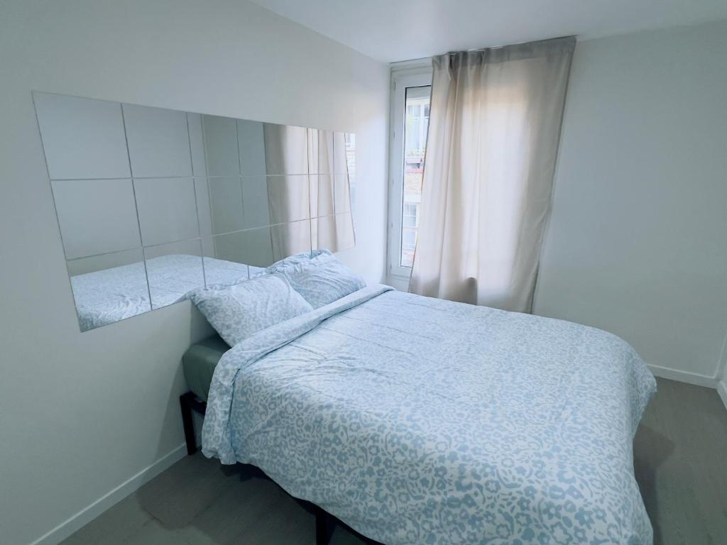 a white bedroom with a bed and a window at X Rooms Appartements & Spa in Villeneuve-Saint-Georges