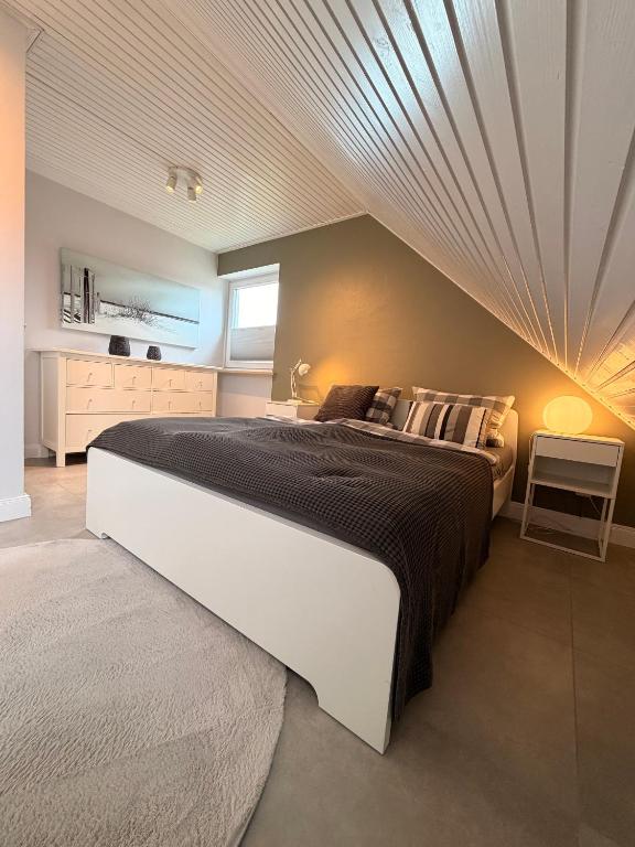 a bedroom with a large bed with a wooden ceiling at Perfekte Wohnung in perfekter Lage mit Balkon! in Westerland