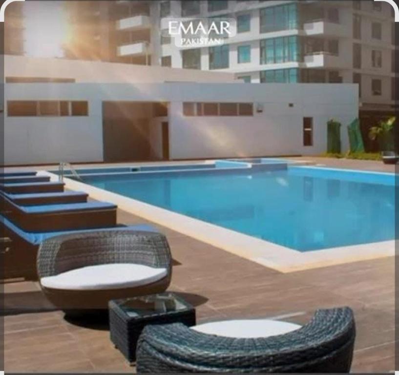 een groot zwembad met stoelen en een groot gebouw bij Le luxe in Karachi